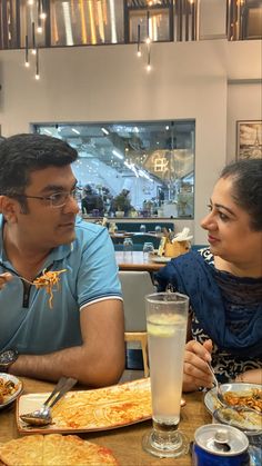 two people sitting at a table with plates of food