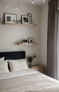 a bed with white sheets and pillows in a bedroom next to a wall mounted shelves