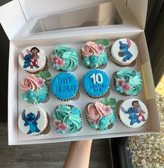 a box filled with lots of cupcakes covered in frosting and decorated to look like cartoon characters