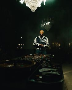 a man standing in front of a table with lots of items on it and a chandelier hanging from the ceiling