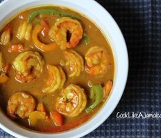 a white bowl filled with shrimp and vegetable soup on top of a blue table cloth