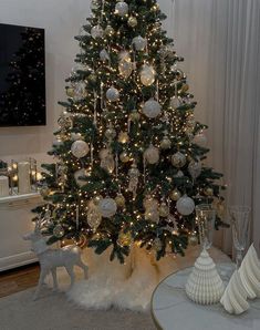 a decorated christmas tree in a living room with white and silver ornaments on the top