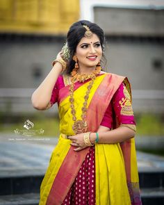 a woman in a yellow and pink sari with gold jewelry on her neck, posing for