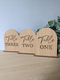 three wooden hearts with words on them sitting on a table next to a potted plant