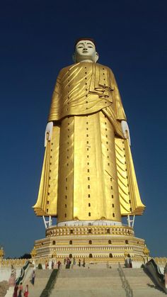 a large golden buddha statue sitting on top of a hill