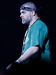 a man with a bandana on his head standing in front of a black background