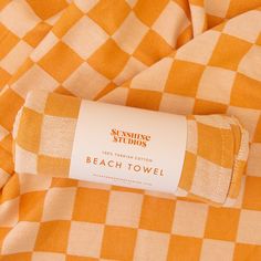 an orange and white checkered beach towel with a label on the end of it