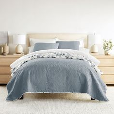 a bed with blue and white comforter in a bedroom next to two nightstands