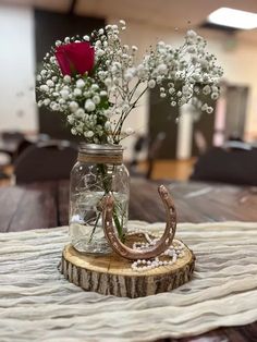 a mason jar filled with water and flowers on top of a wooden table next to a horseshoe