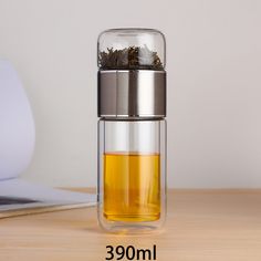 a glass container filled with tea next to a laptop