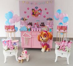 there is a pink and blue birthday party set up with balloons, toys, and decorations