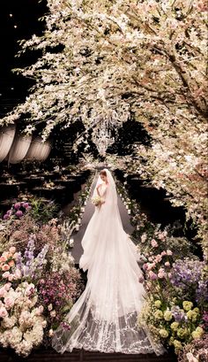 a bride standing in front of flowers and trees