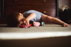 a small child laying on the floor playing with toy cars