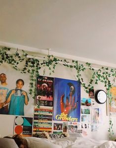 a bedroom with posters on the wall and plants growing from the ceiling, along with a bed