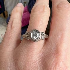 a close up of a person's hand with a diamond ring on their finger