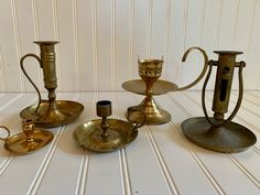 an assortment of antique brass candlesticks and candle holders