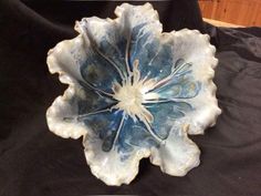 a blue and white flower shaped dish sitting on top of a black cloth