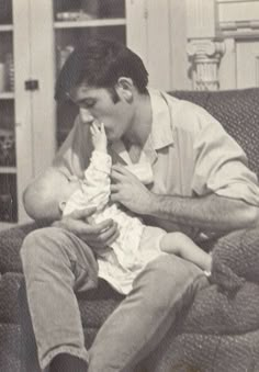 a man sitting on a couch holding a baby