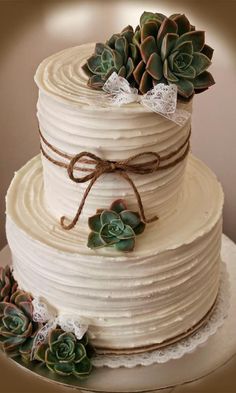 a three tiered cake with succulents and lace on top is shown