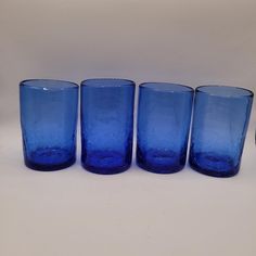 four blue glass tumblers lined up in a row