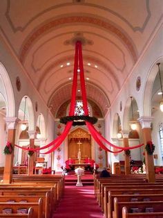 the interior of a church with red ribbon hanging from the ceiling and pews lined up