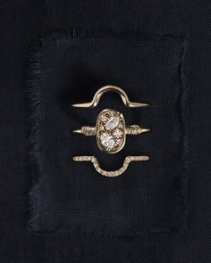 a gold ring with two diamonds on it sitting on a black piece of cloth in front of a white background