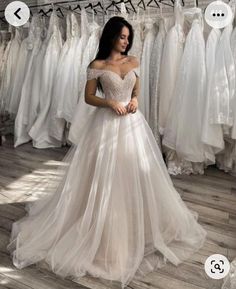 a woman standing in front of a rack of wedding dresses