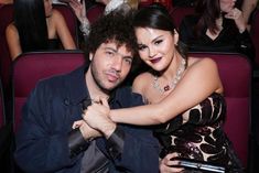 a man and woman sitting next to each other in front of a crowd at an event