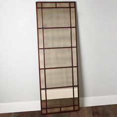 a tall mirror sitting on top of a hard wood floor next to a white wall