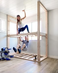 two people are standing on the bottom bunk of a loft bed in an unfinished room