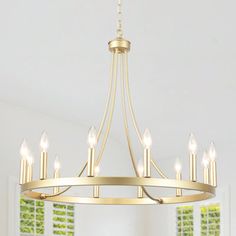 a large chandelier with candles hanging from it's center and two windows in the background