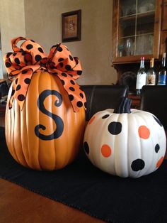 two pumpkins with polka dots and a bow on them are sitting on a table