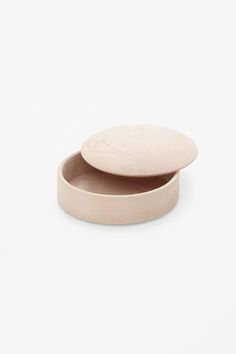 two wooden plates sitting side by side on a white surface, one is empty and the other has a lid