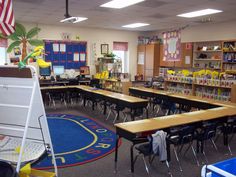 an empty classroom with desks and chairs in front of the bookshelves is shown