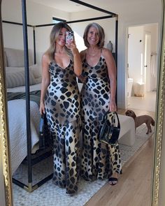 two women standing in front of a mirror taking a selfie with their cell phone