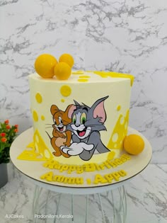 a birthday cake with an image of a cat and mouse on it, surrounded by lemons