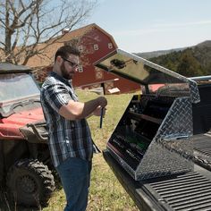 a man standing next to an atv holding a tool