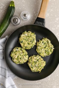 zucchini patties with spinach and cheese in a frying pan