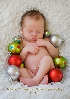 a baby is laying down with christmas ornaments around his body and hands on his chest