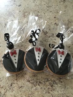 three decorated cookies in the shape of tuxedos