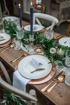 the table is set with candles, plates and napkins