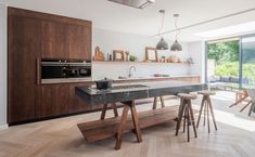 a modern kitchen with an island in the middle and wooden cabinets on both sides, along with glass doors leading outside