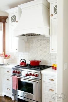 a stove top oven sitting inside of a kitchen next to white cabinets and counter tops