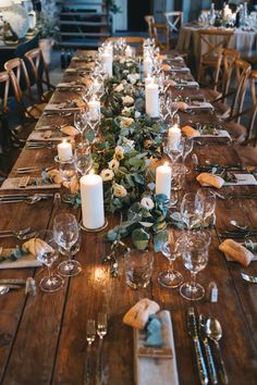 the table is set with candles and greenery for an elegant dinner party or special event