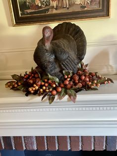 a turkey statue sitting on top of a mantle next to berries and acorns