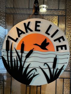 a lake life sign hanging from the side of a building with water and reeds