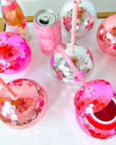 there are many pink and silver disco ball drinks on the table with their straws