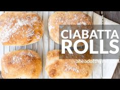 four rolls on a cooling rack with the words ciabatta rolls above them in white