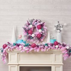 a fireplace decorated with pink, blue and white christmas wreaths on top of it