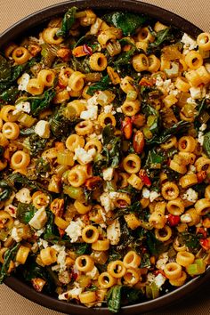 a pan filled with pasta and spinach on top of a table